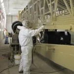 Empleado aplicando la grasa anticorrosiva ZERUST Axxanol Spray-G en equipos grandes para protección contra la corrosión.