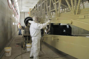 Empleado aplicando la grasa anticorrosiva ZERUST Axxanol Spray-G en equipos grandes para protección contra la corrosión.