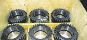 Engranajes metálicos en una caja que muestra un empaquetado avanzado contra la corrosión.