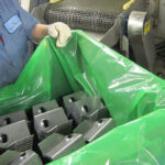 Empleado de manufactura transportando partes estampadas en Película VCI ZERUST