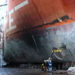 Vista amplia del granallado con vapor húmedo en el casco de un barco